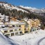 Hotel in legno su una collina innevata con montagne e alberi sullo sfondo